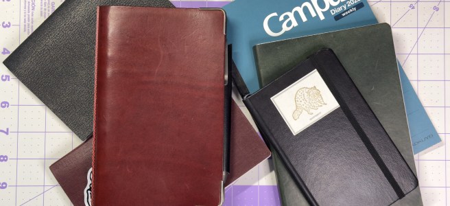 A stack of notebooks and planners used in 2024 and 2025